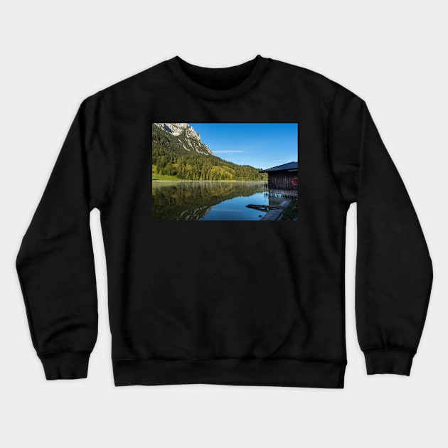 Lake water reflections with wooden boathouse wide angle. Amazing shot of a wooden house in the Ferchensee lake in Bavaria, Germany, in front of a mountain belonging to the Alps. Crewneck Sweatshirt by EviRadauscher